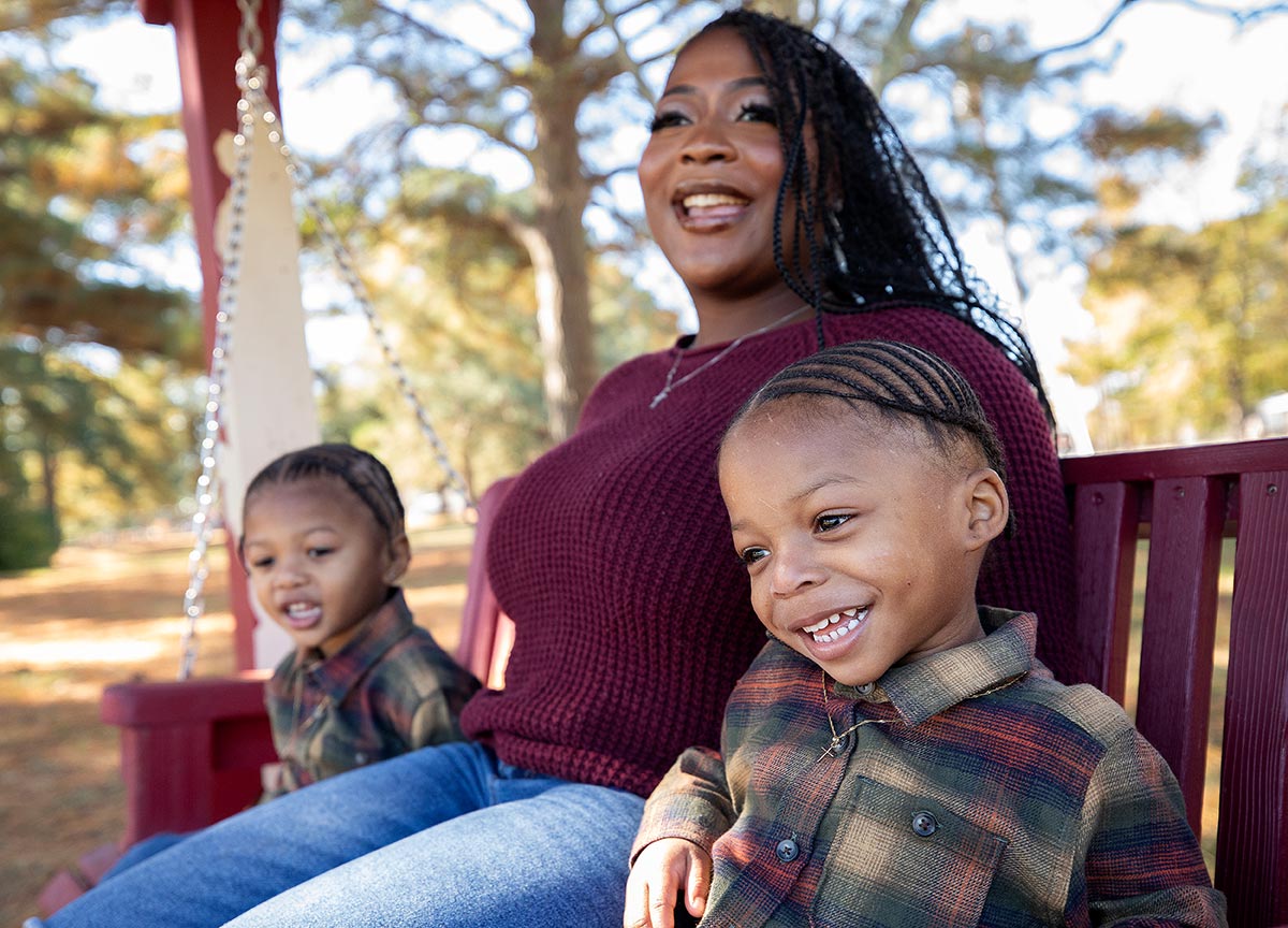 Mother and children smiling on a swinging bench