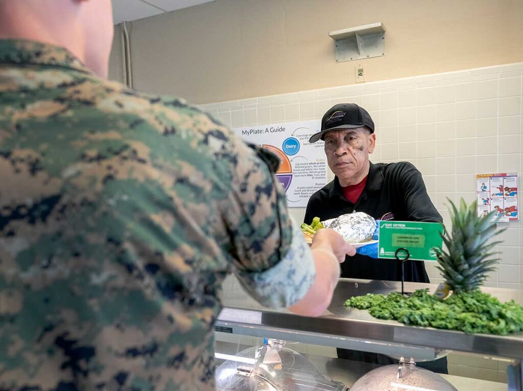 A man serves food to a soldier while working at the Yorktown Naval Weapons Station mess hall