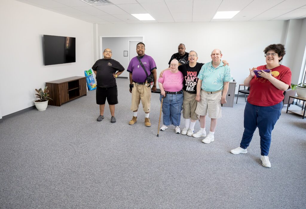 A group of people stand next to each other and smile in a room in the Puller Center