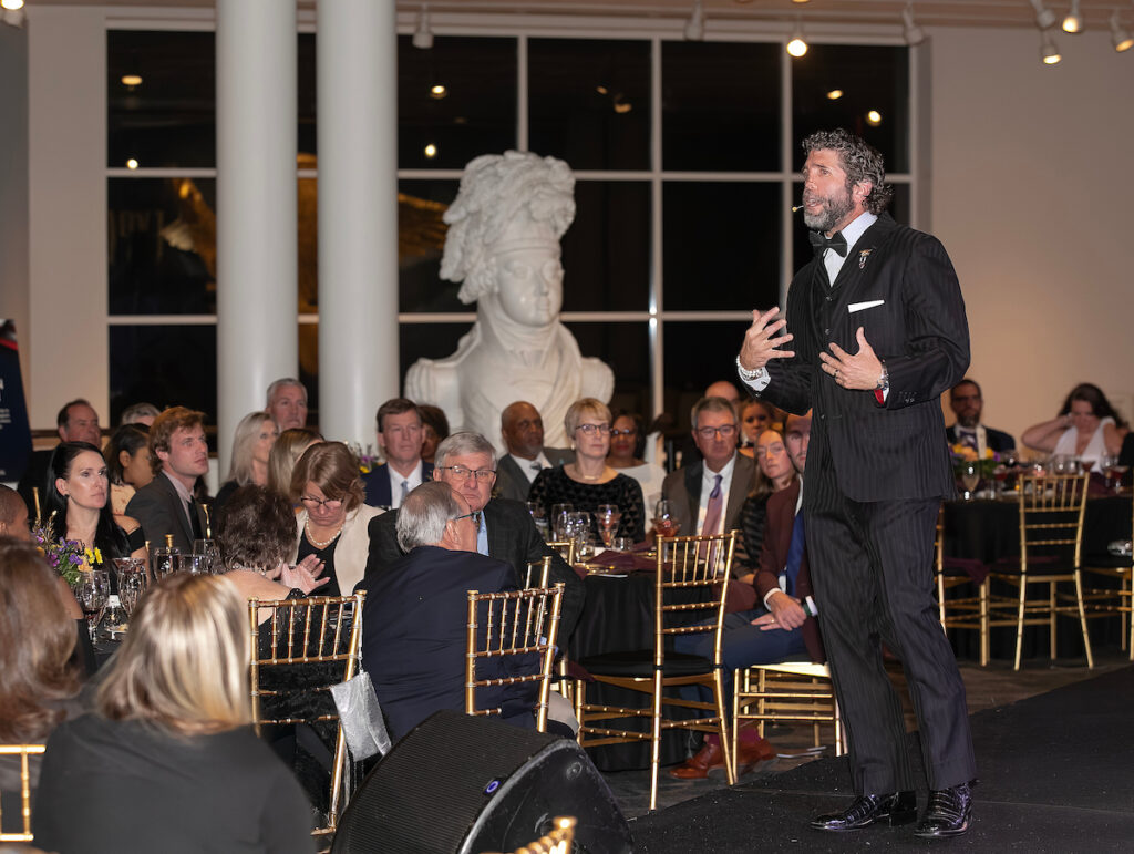Jason Redman holding his “Attention” sign while speaking on stage at VersAbility’s 2025 Gala