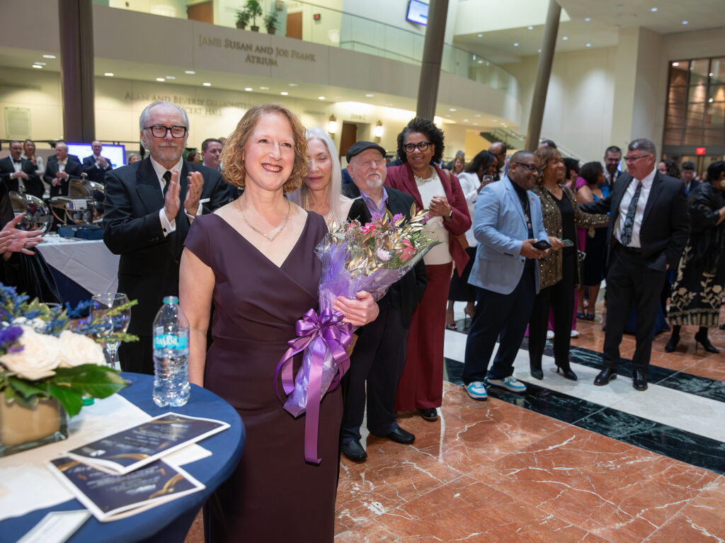 President and CEO of VersAbility Resources holding a bouquet of flowers at an awards ceremony. 