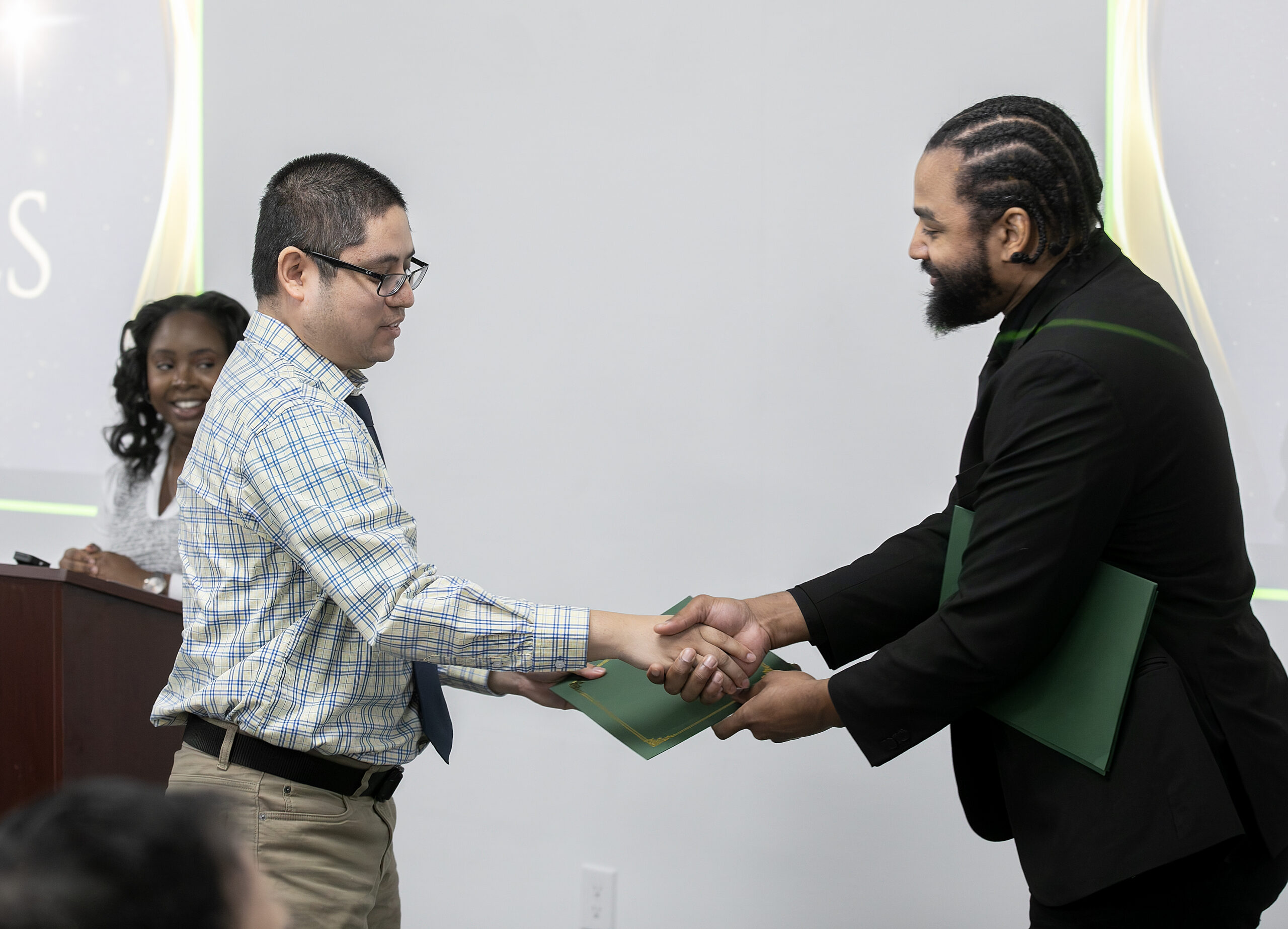 Two men shake hands at a graduation ceremony for the abilIT Program from VersAbility Resources.