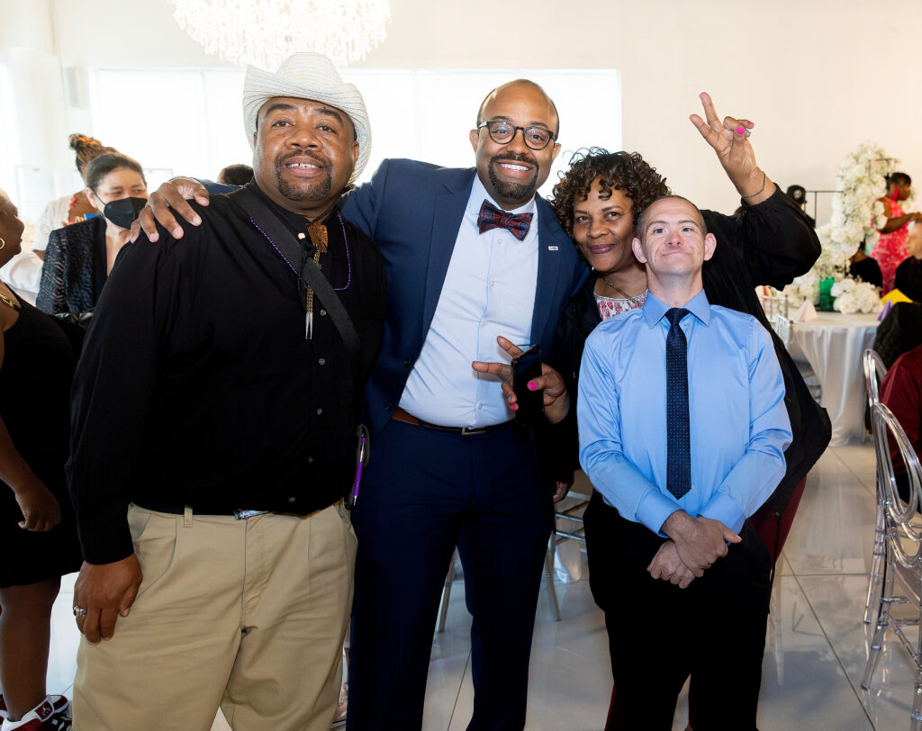 A group of people with their arms around each other, smiling for the camera 