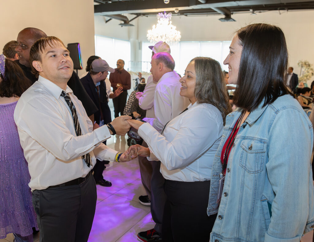 Group of people in suits and dresses smiling and dancing