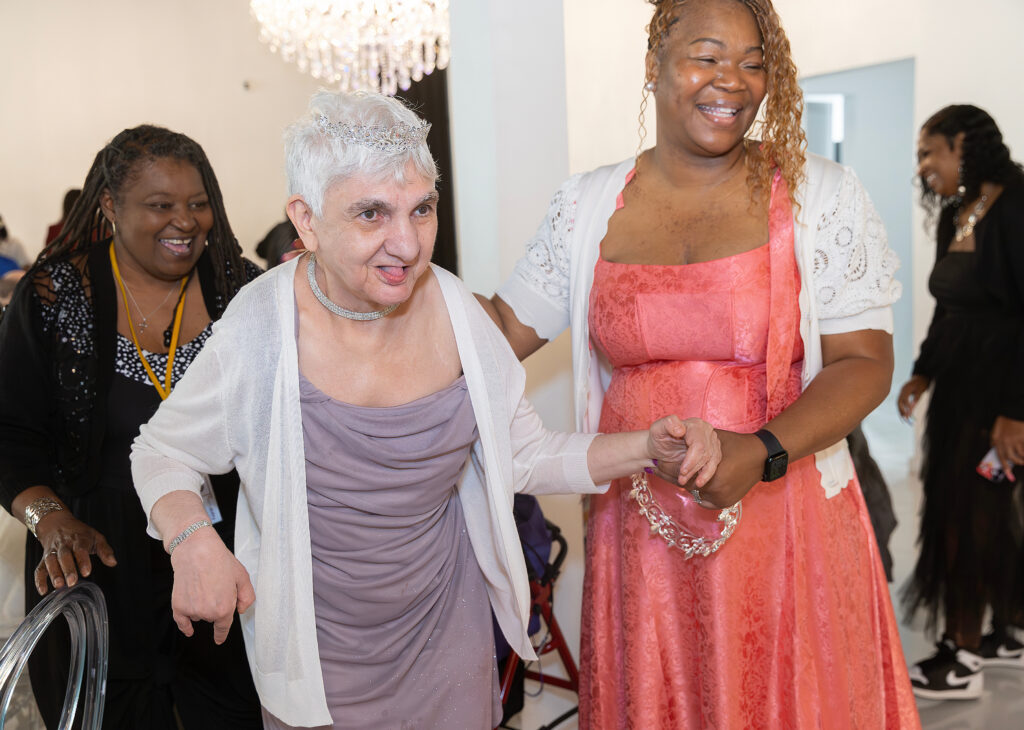 Three women in gowns smiling as they look off camera